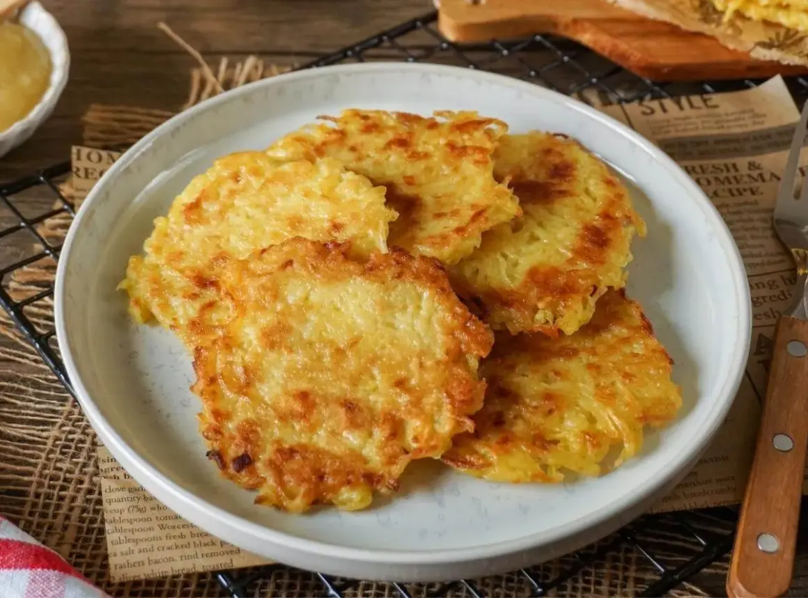 Goldbraune, knusprige Kartoffelpuffer aus gekochten Kartoffeln liegen auf einem Teller. Dazu passt Apfelmus.
