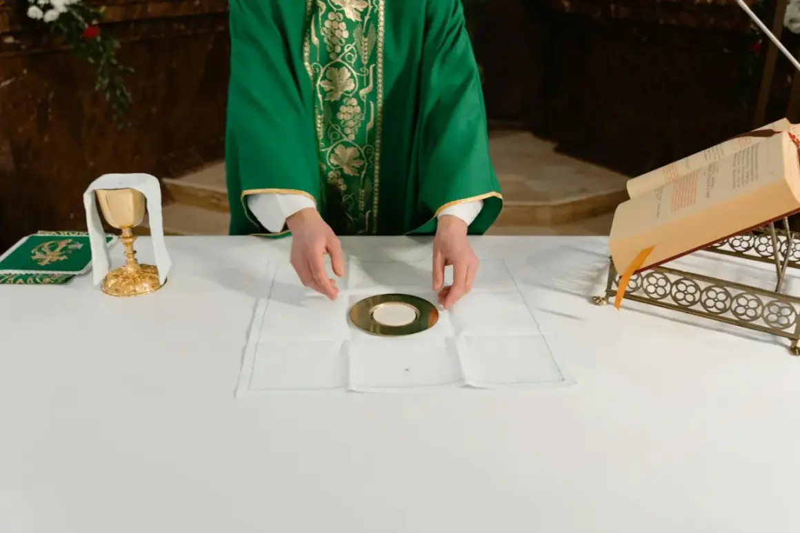 Kapłan przygotowuje się do udzielenia komunii. Na ołtarzu kielich, patena z hostią i księga.