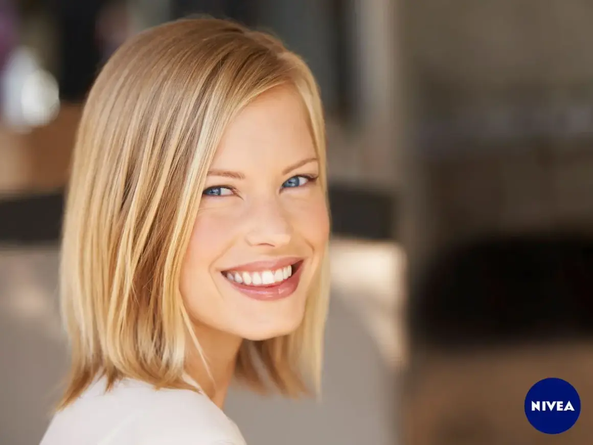 Lächelnde Frau mit blondem Bob, ein moderner **haarschnitt frauen**. Ihr Blick ist strahlend, die Haut makellos.