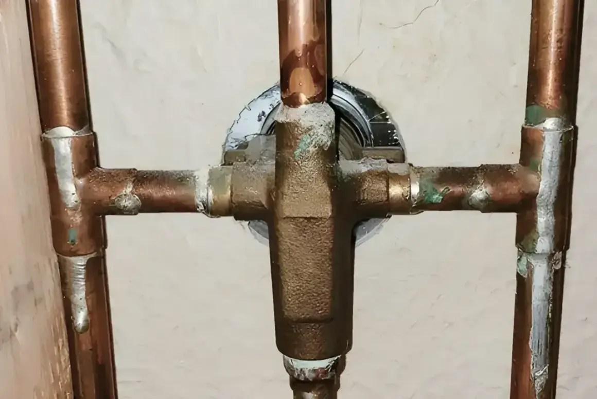 Plomberie en cuivre avec dépôts verts, signe des inconvénients de l'eau trop douce qui corrode le métal.