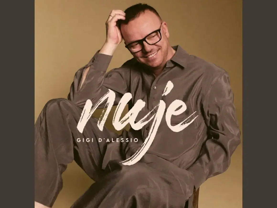 Gigi D'Alessio sorride, con la mano tra i capelli. Sulla sua camicia, la scritta "Nuje". Chissà cosa ci spiegate cherè.