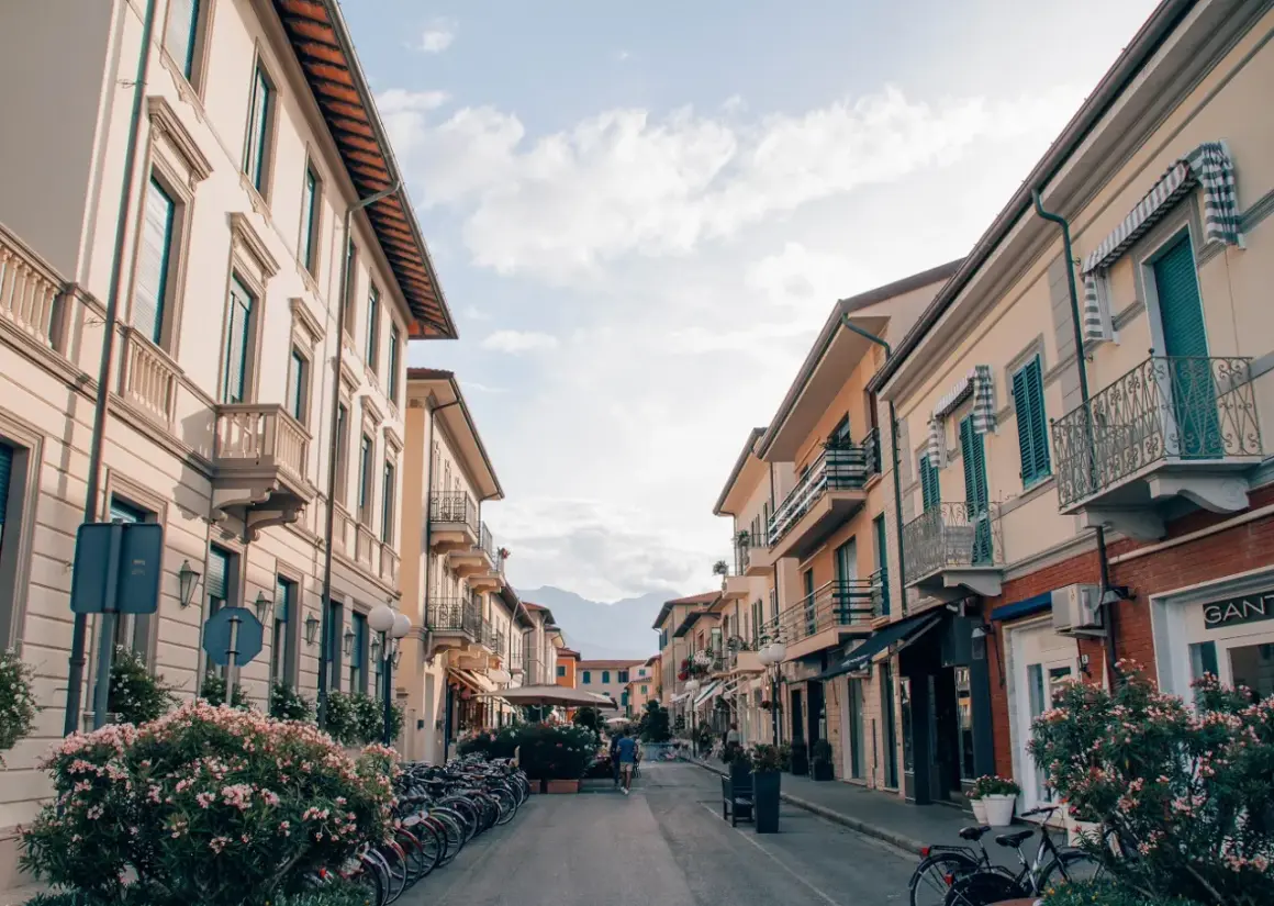 Strada pittoresca a Forte dei Marmi, Italia, con palazzi color pastello, balconi in ferro battuto e biciclette parcheggiate.