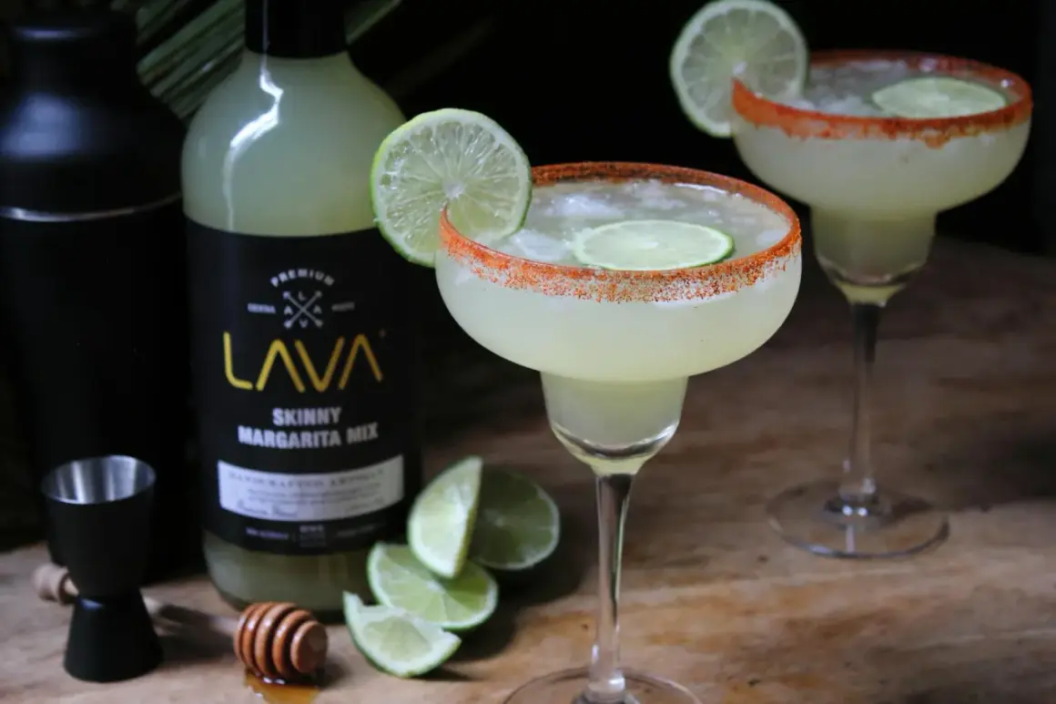 Idealny margarita przepis z mixem LAVA. Dwa drinki z solą i limonką, shaker, miarka i plasterki limonki.