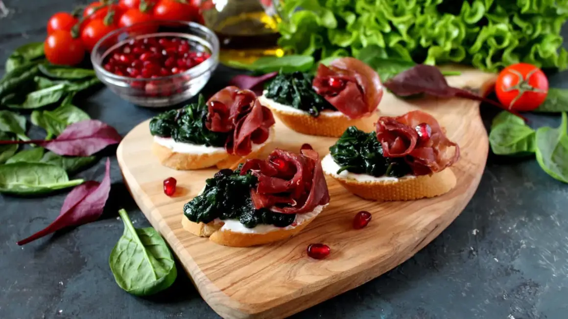 Leckere Bruschetta mit Spinat, Schinken und Granatapfelkernen – eine tolle Kombination eisenhaltiger Lebensmittel.