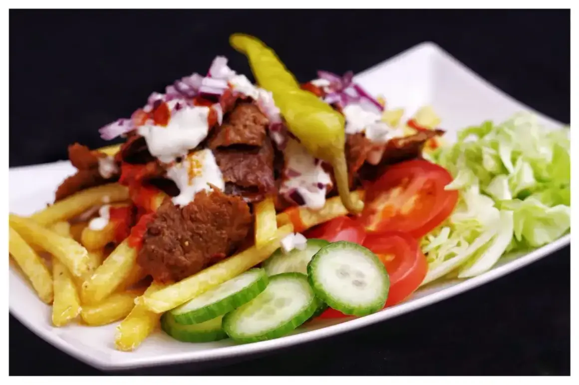 En tallrik med kebab, pommes frites, tomater, gurka, sallad och en stark chili. Perfekt för dig som söker ett gott kebabsås recept.