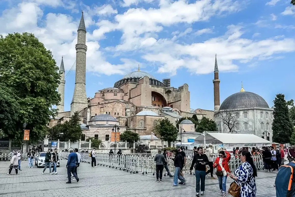 Tłum ludzi spaceruje przed majestatyczną Hagia Sophia w Stambule, podziwiając jej architekturę.