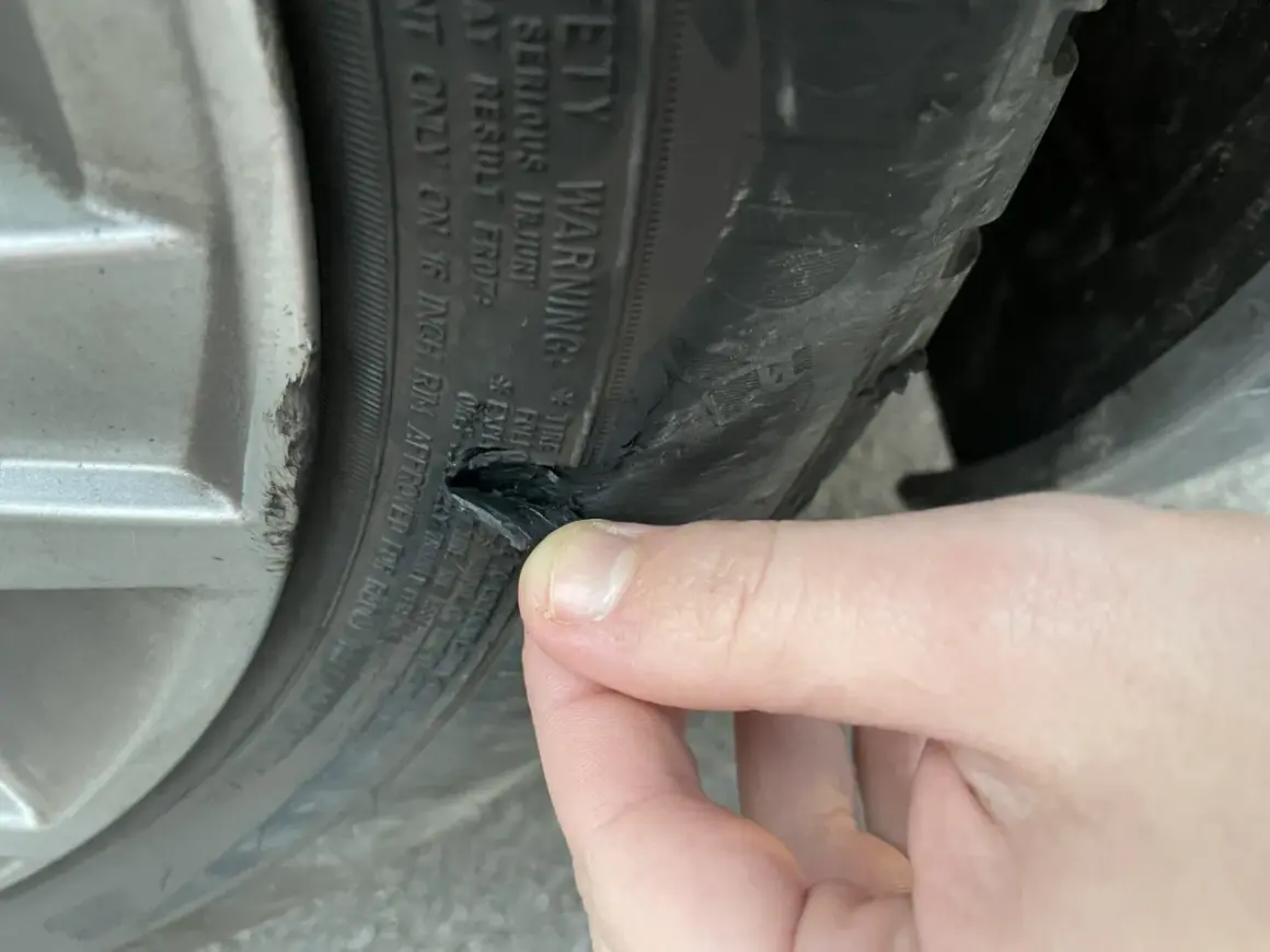 Un pneu abîmé sur le flanc, probablement suite à un choc contre le trottoir. La gomme est déchirée.