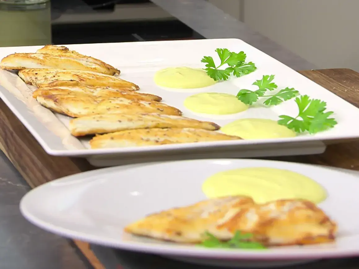 Pescado dorado a la plancha con salsa cremosa y perejil fresco. Un plato ligero y sabroso.