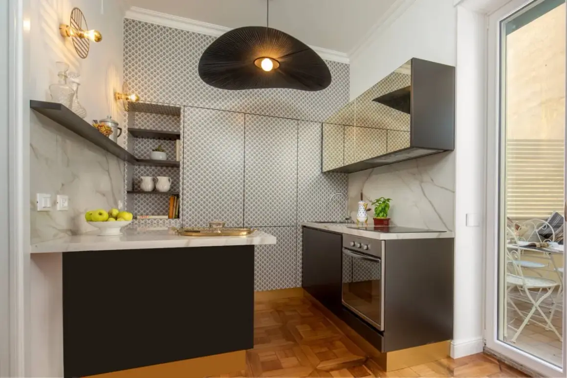Cucine piccole ma eleganti, con piano in marmo, pensili a specchio e un'originale lampada a sospensione.