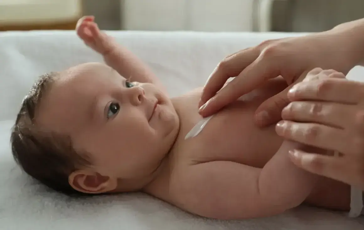 Delikatna pielęgnacja 2 miesięcznego dziecka. Kremowanie jego skóry to chwila bliskości i troski.