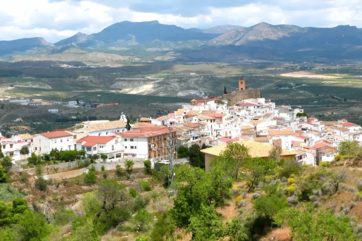 Vista panorámica de las menas Almería, un pueblo blanco en una ladera con montañas al fondo.