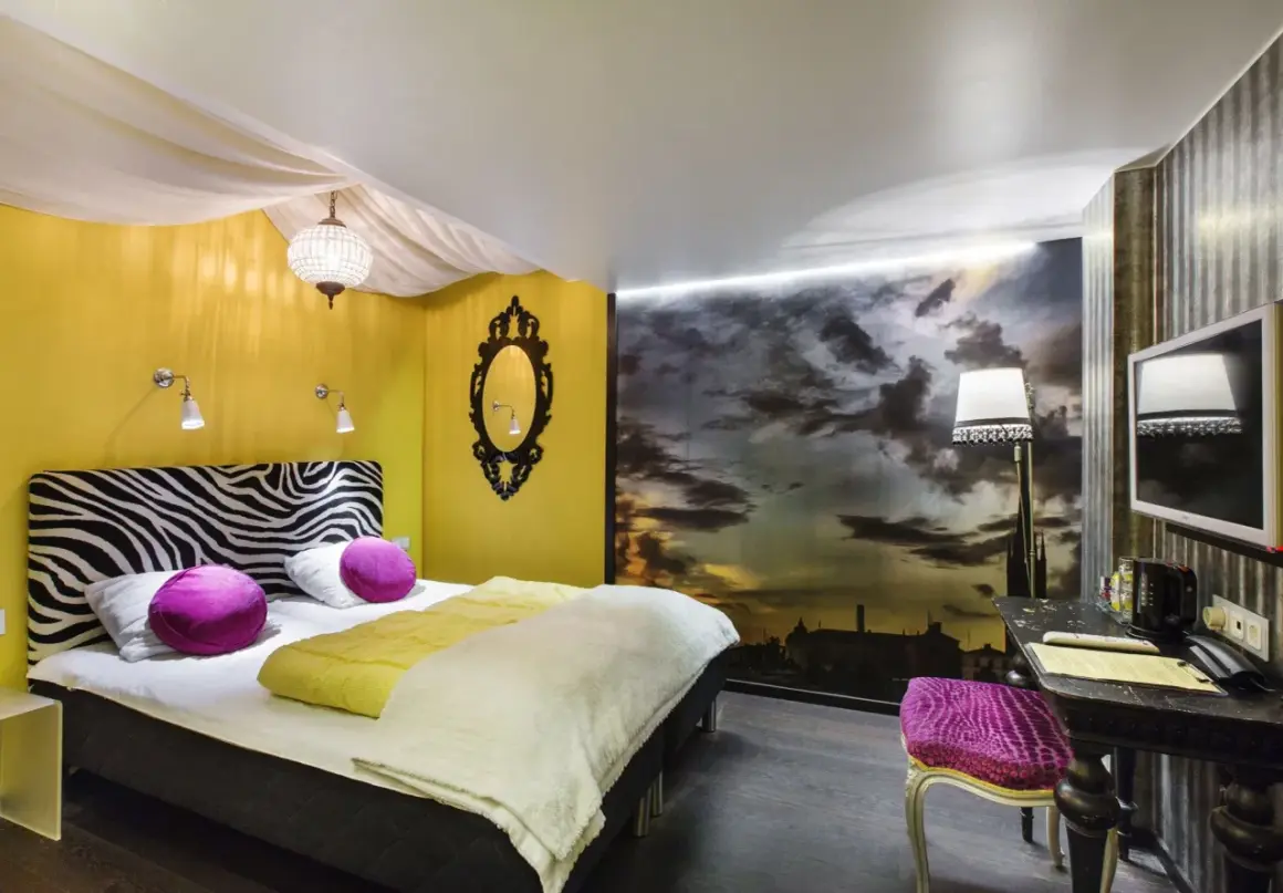 Ett mysigt eget rum på vandrarhem i Stockholm med zebra-mönstrat sänggavel, gul vägg och dramatisk molnhimmel som fondtapet.