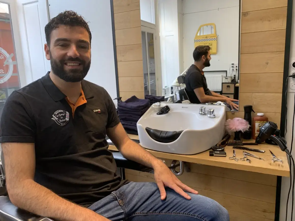 Le tonsor souriant, barbier dans son salon, entouré de ses outils de coiffure.