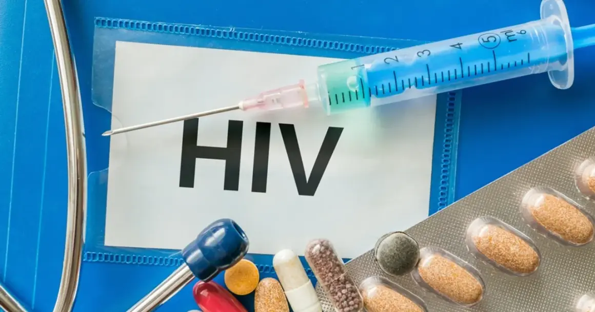 Strzykawka, tabletki i stetoskop na tle napisu HIV.