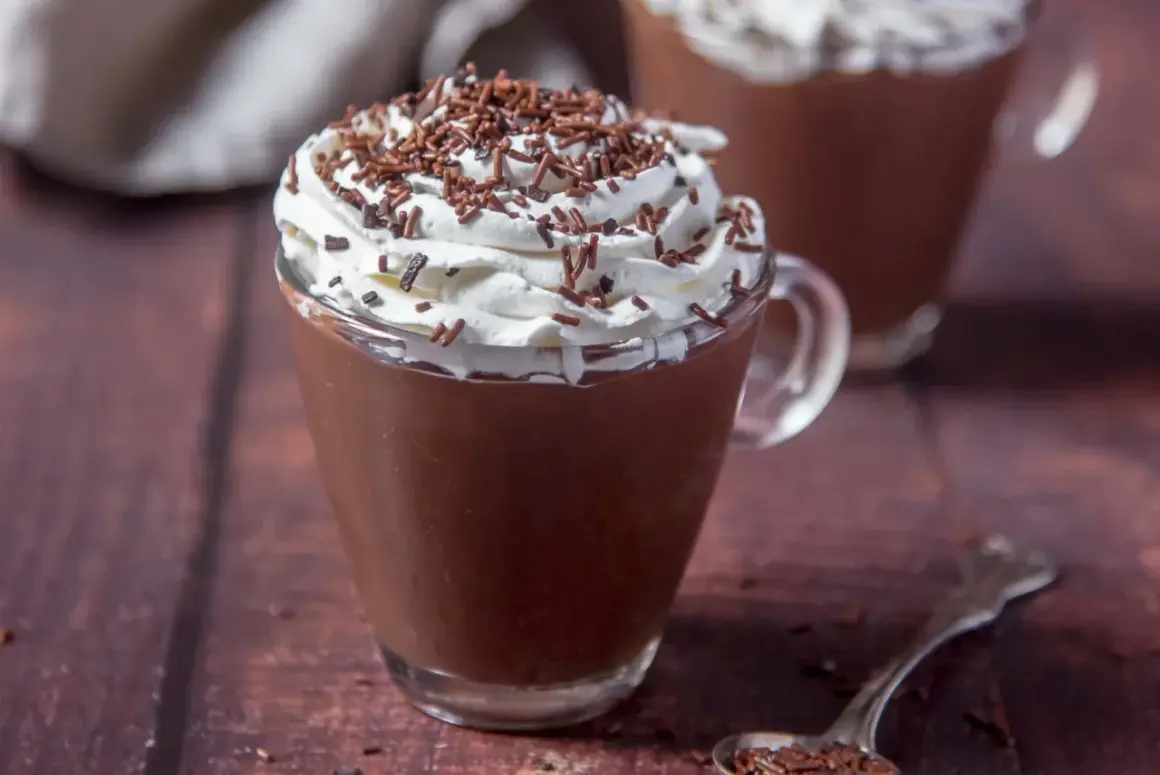 Cioccolata calda con acqua e cacao, guarnita con panna montata e codette di cioccolato. Un comfort food perfetto per riscaldarsi.