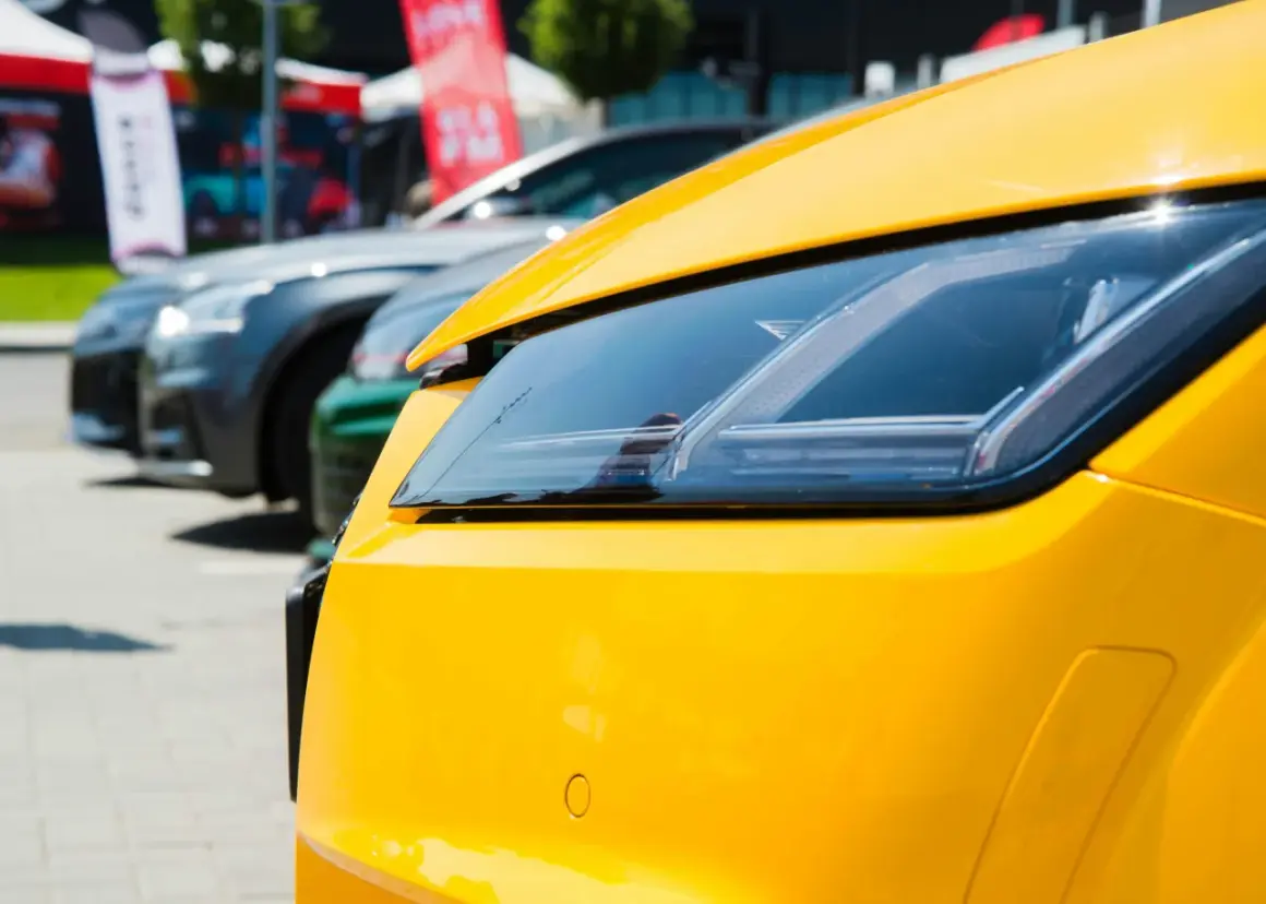 Gros plan sur le phare d'une voiture jaune vif, avec d'autres voitures en arrière-plan. Pensez à la résiliation de votre assurance auto pour ce bolide.