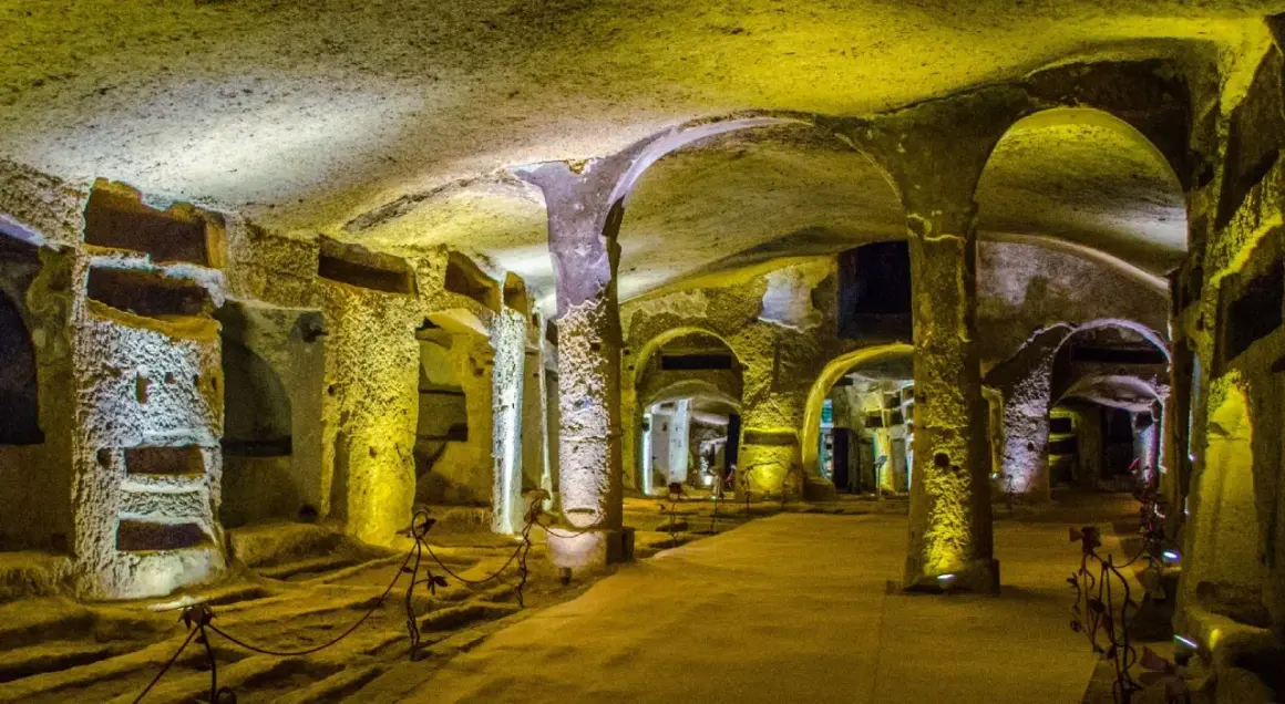 Un viaggio nelle catacombe di San Gennaro, un luogo suggestivo con tombe scavate nella roccia e colonne antiche.