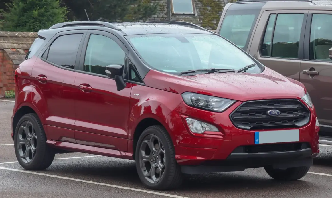 Czerwony Ford EcoSport 2018 z czarnym dachem, zaparkowany na mokrym parkingu.