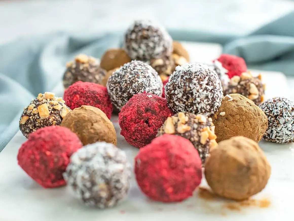 En hög med läckra dadelbollar recept, täckta med kokos, nötter och hallonpulver. Perfekta som energiboost!