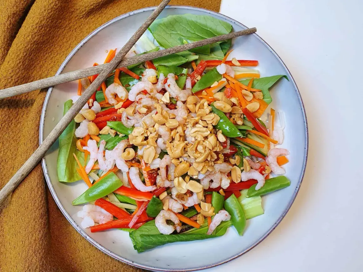 En fräsch asiatisk nudelsallad med räkor, grönsaker och jordnötter. Perfekt för en lätt lunch eller middag.