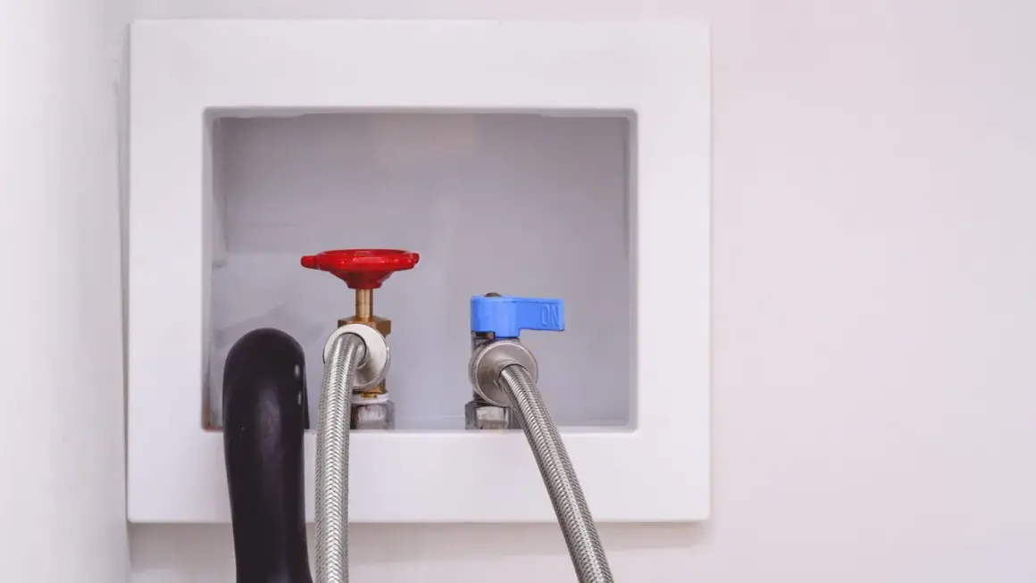 Washing machine installation: water inlet valves with hoses attached, ready for hookup.