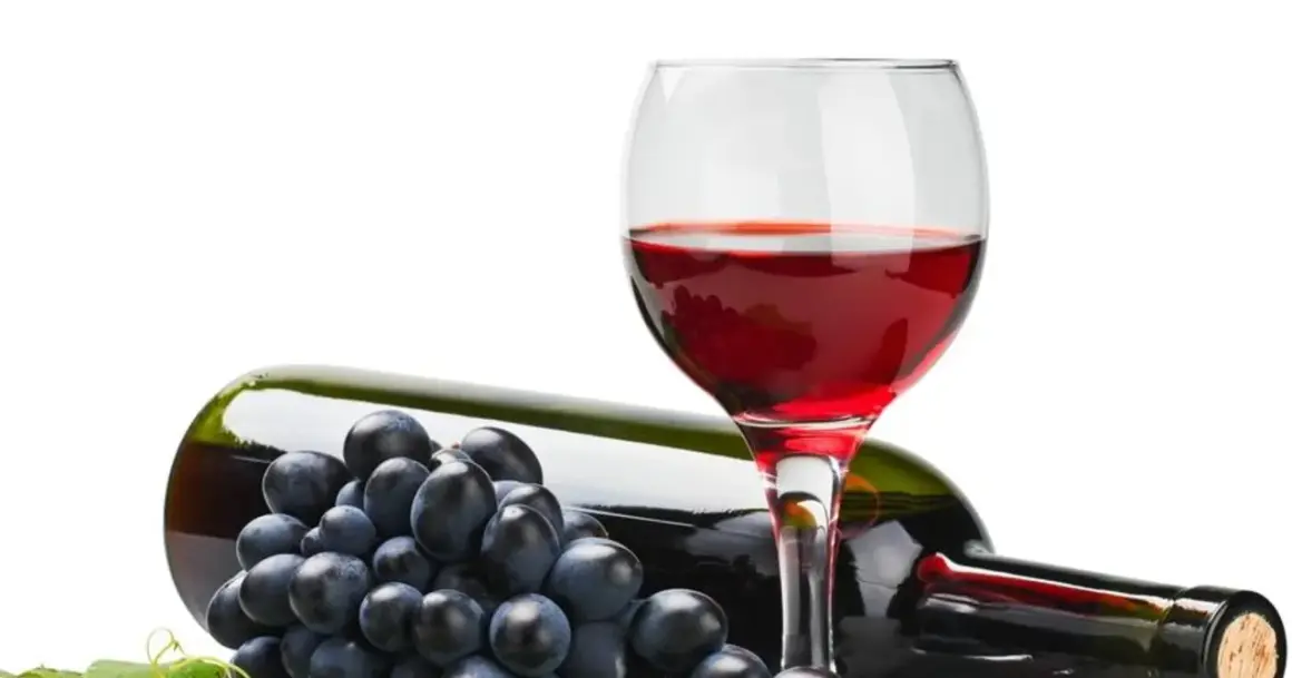 Czerwone wino w kieliszku, butelka i winogrona. Czy wiesz, że resweratrol co to jest, znajduje się w skórce winogron?