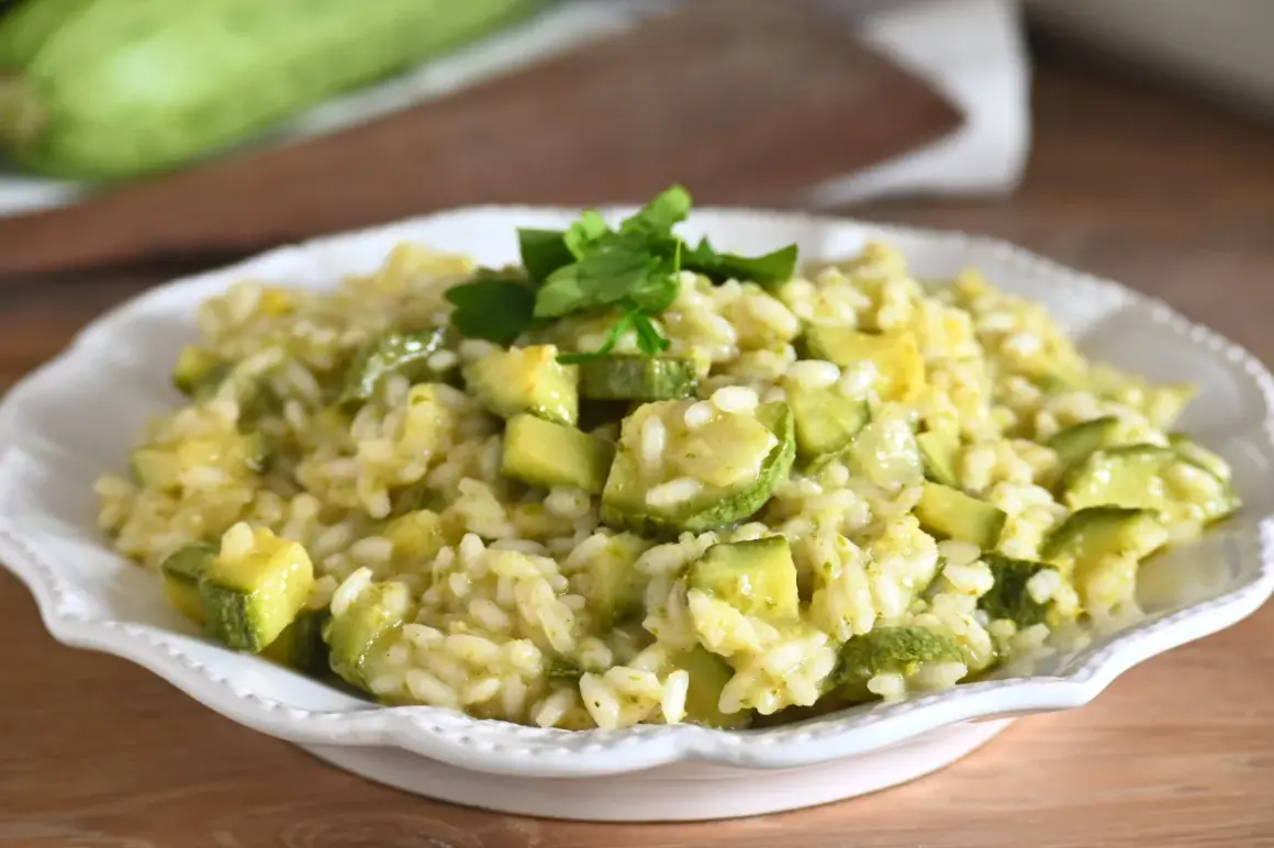 Un cremoso risotto con zucchine fresche, cotto in padella e guarnito con prezzemolo. Un piatto leggero e saporito.