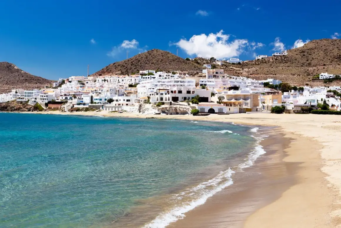 Un pueblo blanco se asoma a una playa dorada y aguas turquesas. Un lugar idílico que ver en Cabo de Gata.