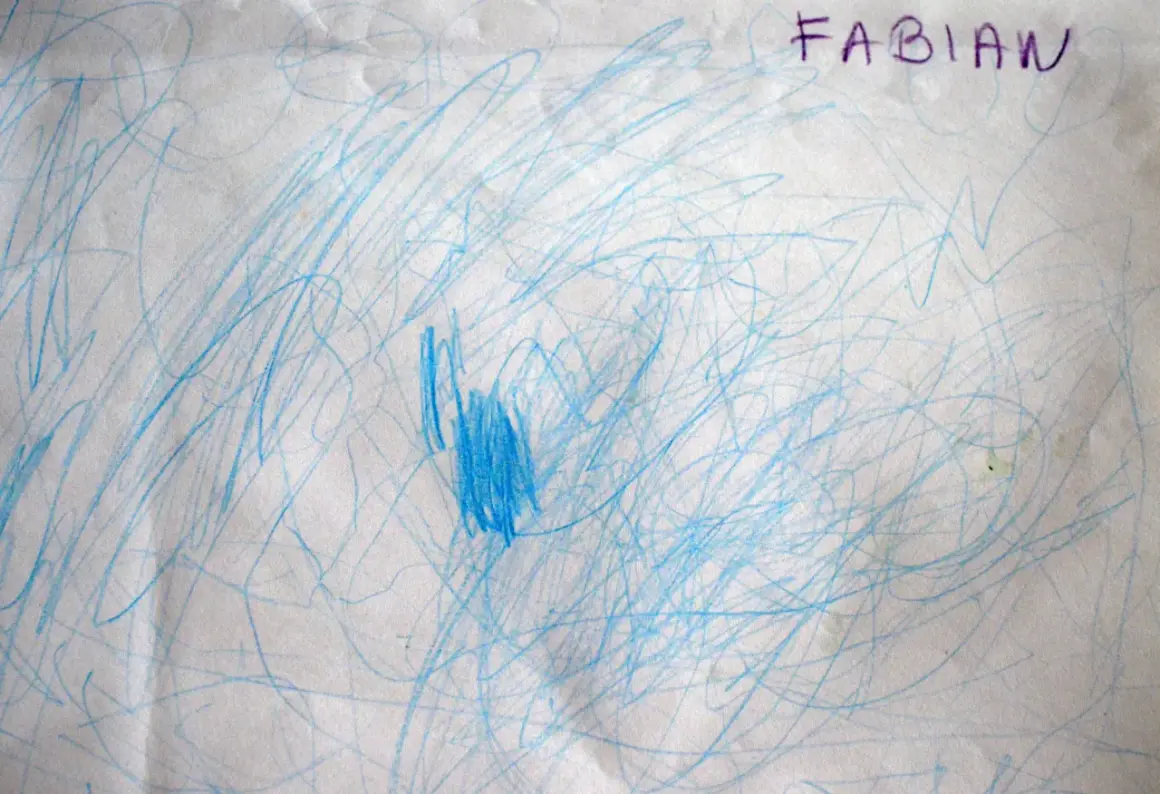 Niebieskie bazgroły na papierze, podpisane "FABIAN". To początkowe etapy rysunku dziecka, pełne ekspresji i wyobraźni.