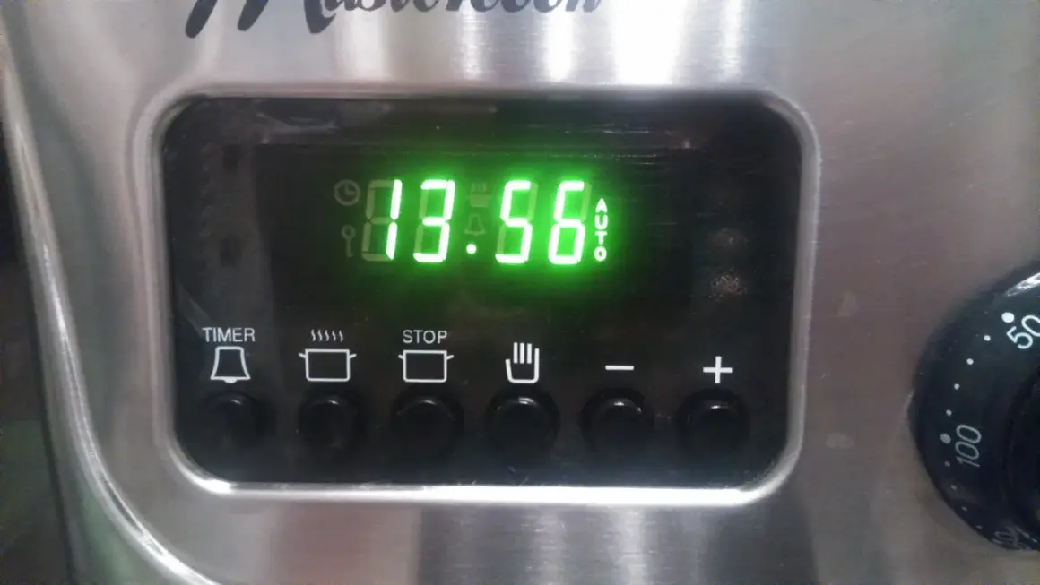 Cyfrowy wyświetlacz piekarnika Mastercook pokazuje godzinę 13:56. Ikony sugerują funkcje timera, gotowania, stopu i automatycznego trybu.