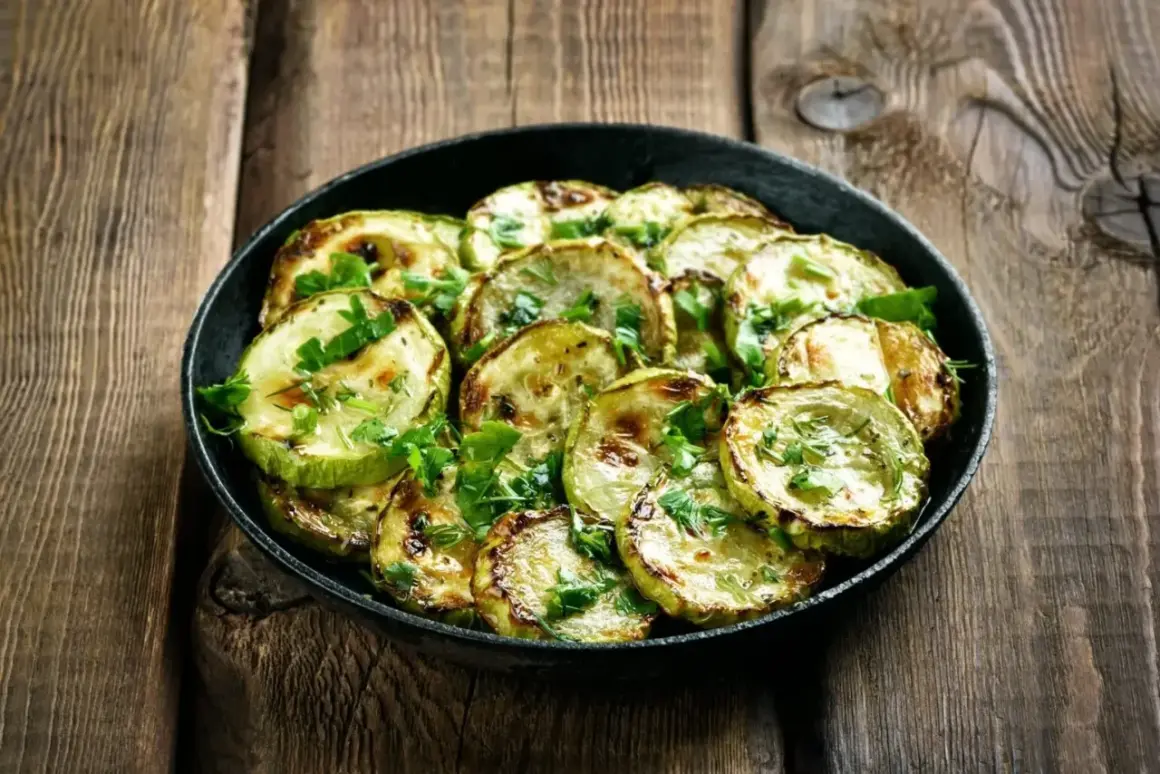 Zucchine marinate cotte, grigliate e guarnite con prezzemolo fresco, servite in una padella su un tavolo di legno rustico.