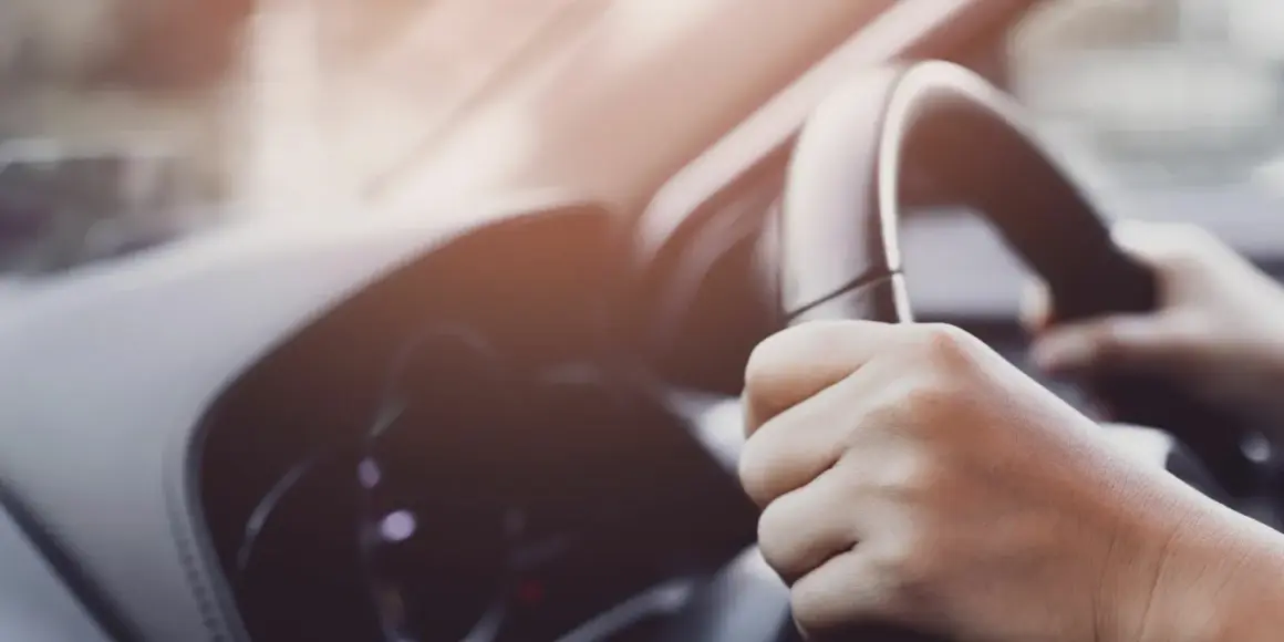 Manos sujetando el volante de un coche, con un ligero ruido al girar el volante.