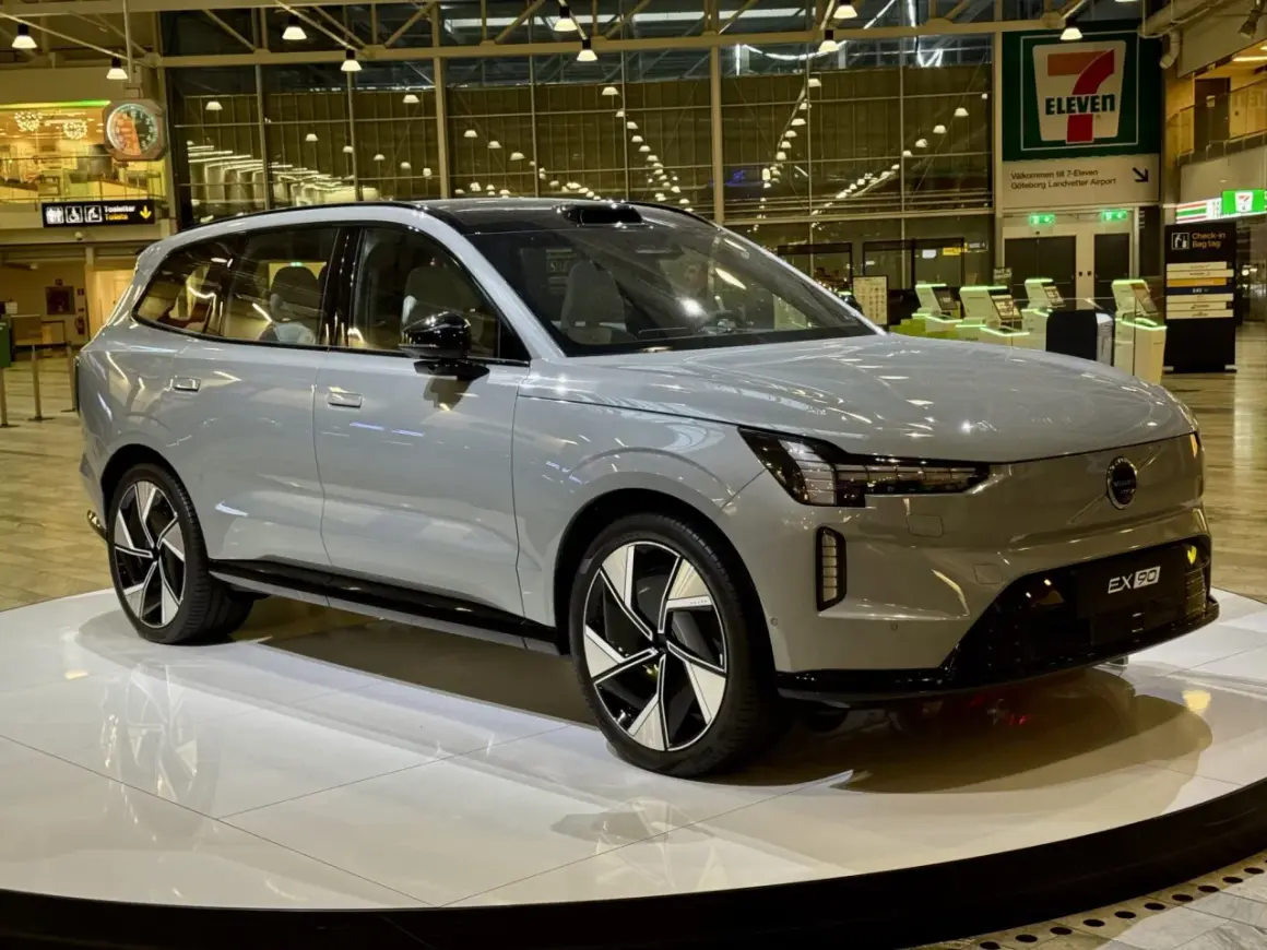 Grå Volvo EX90 på en utställningsplattform. Framtiden för volvo car mobility visas upp på flygplatsen.