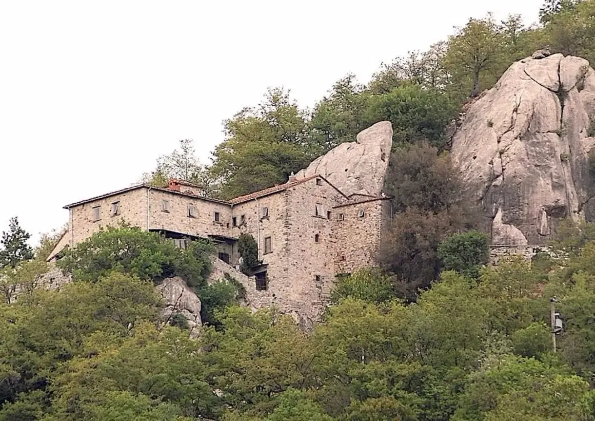 Antica pieve in pietra a Pieve Santo Stefano, incastonata tra rocce e alberi secolari, testimone di storia.