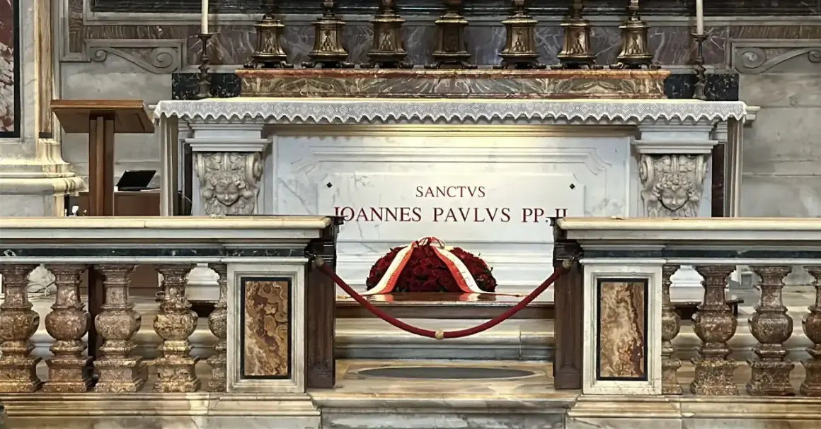 Grób Jana Pawła II w Watykanie. Marmurowa płyta z napisem "Sanctus Ioannes Paulus PP. II" i wieniec z czerwonych róż.