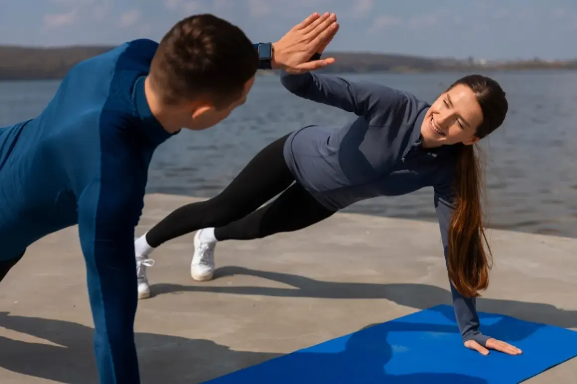 Para ćwiczy na macie nad wodą, wykonując boczne deski i dając sobie high five. Idealny sport dla par.
