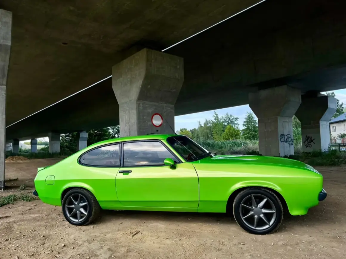 Zielony Ford Capri z lat 70. pod betonowym wiaduktem.