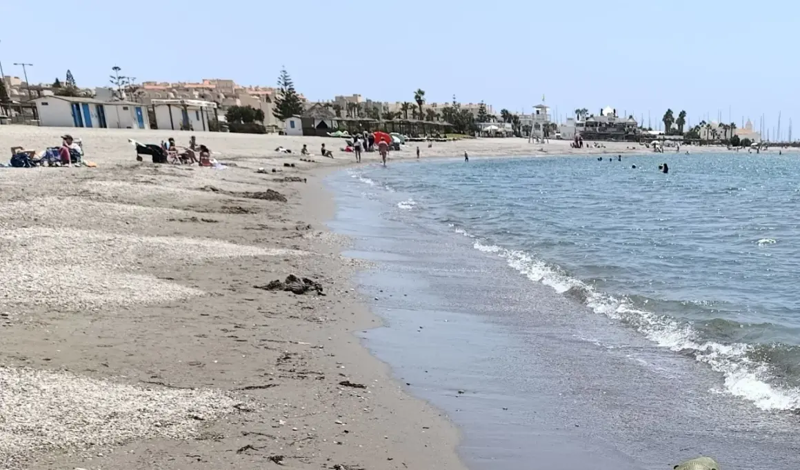 Gente disfrutando de un día soleado en la playa de Almerimar. Las opiniones sobre este lugar son muy positivas, ideal para relajarse.