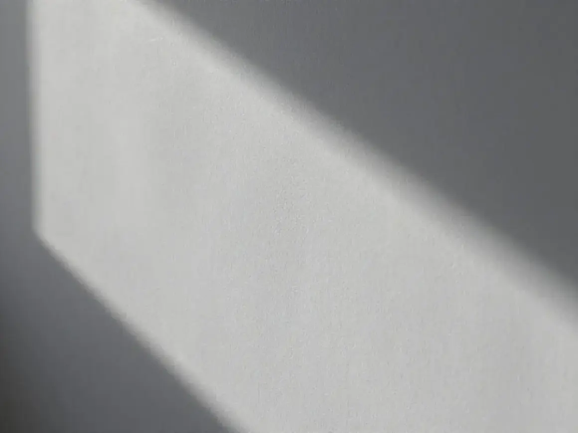 Światło podkreśla nierówności na elewacji, tworząc cień o geometrycznym kształcie.