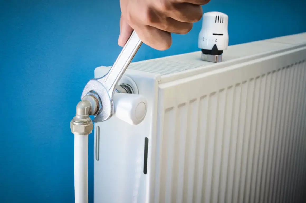 Réparation d'un radiateur bruyant. Une clé serre un raccord, peut-être pour arrêter l'eau qui coule.