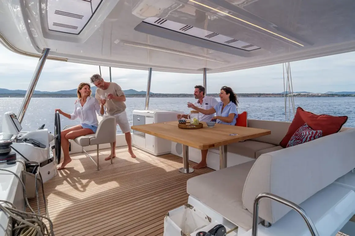 Coppia felice brinda a bordo di un catamarano, godendosi il sole e il mare. Interni eleganti e confortevoli.
