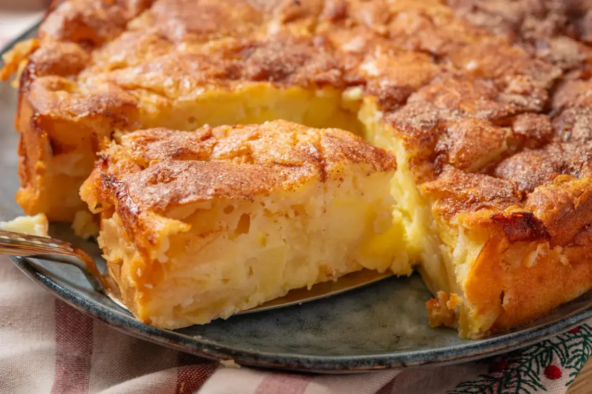 Ein goldbrauner Apfelkuchen, der nach einem einfachen Apfelkuchen Rezept duftet. Ein Stück wird mit einer Gabel herausgehoben.