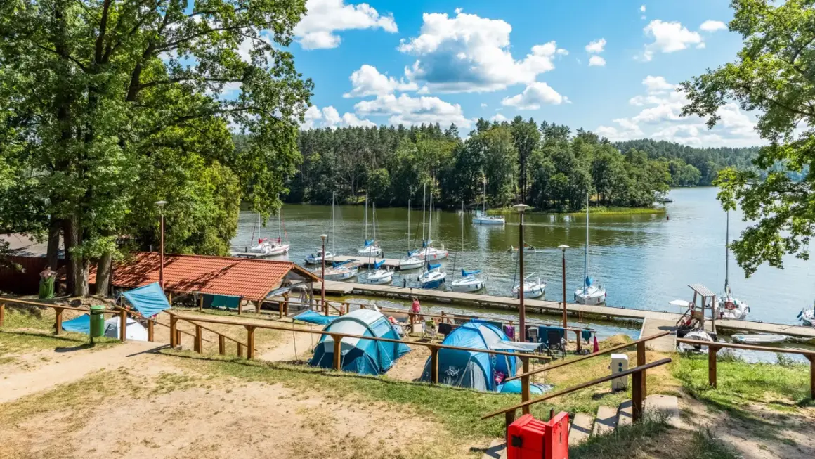 Namioty rozbite nad jeziorem, gdzie cumują żaglówki. Idealne miejsce na wypoczynek, prawdziwy pole namiotowe Mazury.