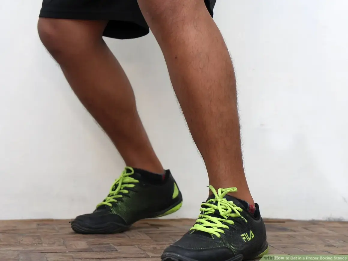 A boxer demonstrates the correct orthodox boxing stance, with feet planted and knees slightly bent, ready to move.