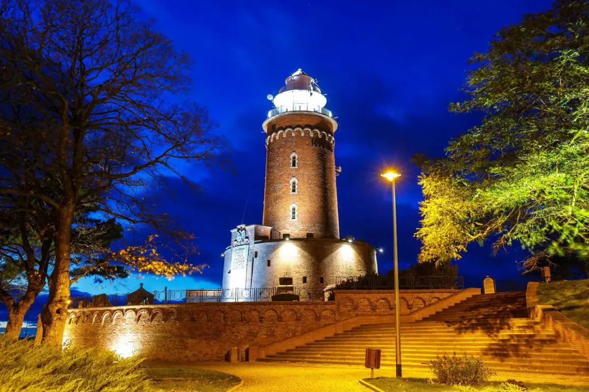 Wieczorem rozświetlone latarnie morskie polska, otoczone drzewami i schodami, tworzą magiczny widok.