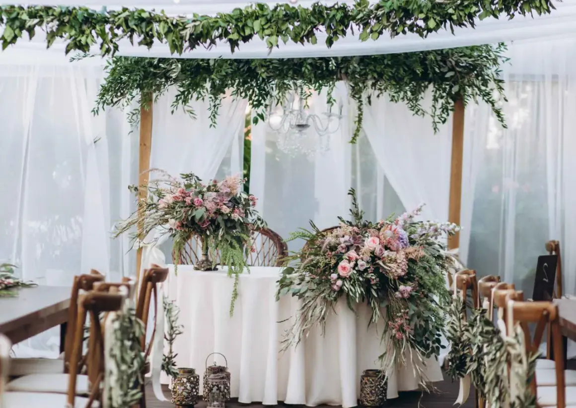 Udekorowany bukietami kwiatów stół i krzesła tworzą romantyczną stylizację boho na wesele.