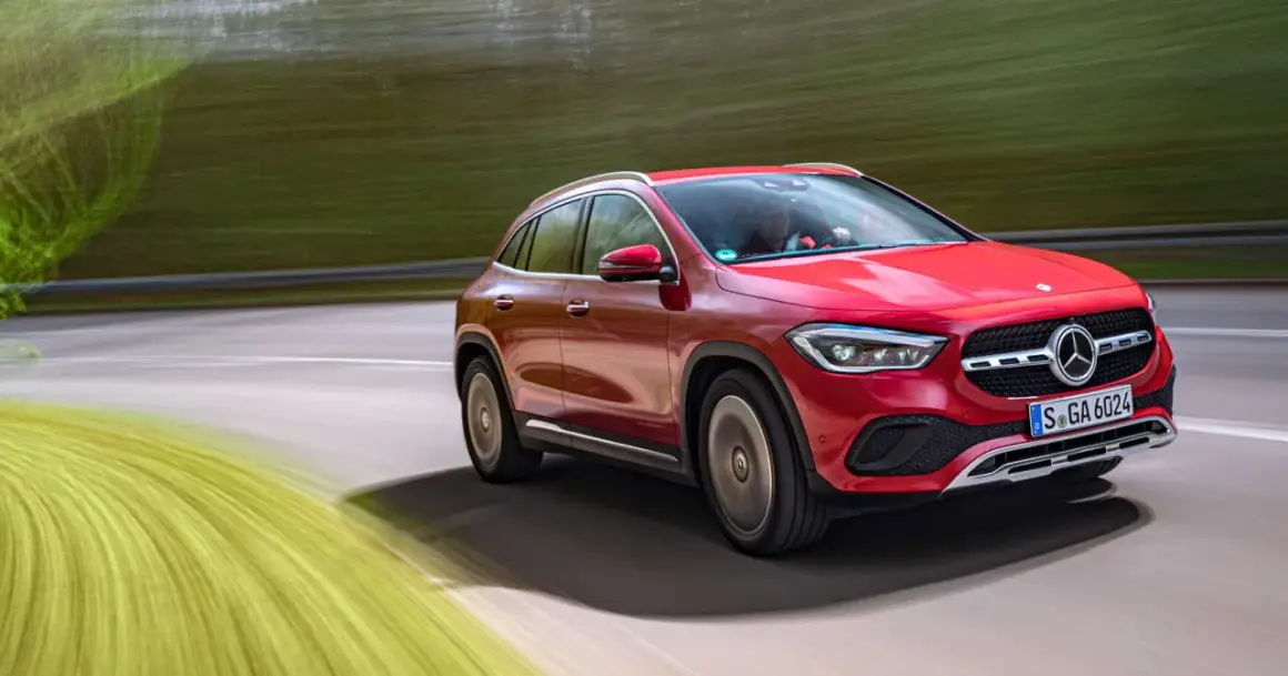 Röd Mercedes GLA på en testkörning längs en grönskande väg.
