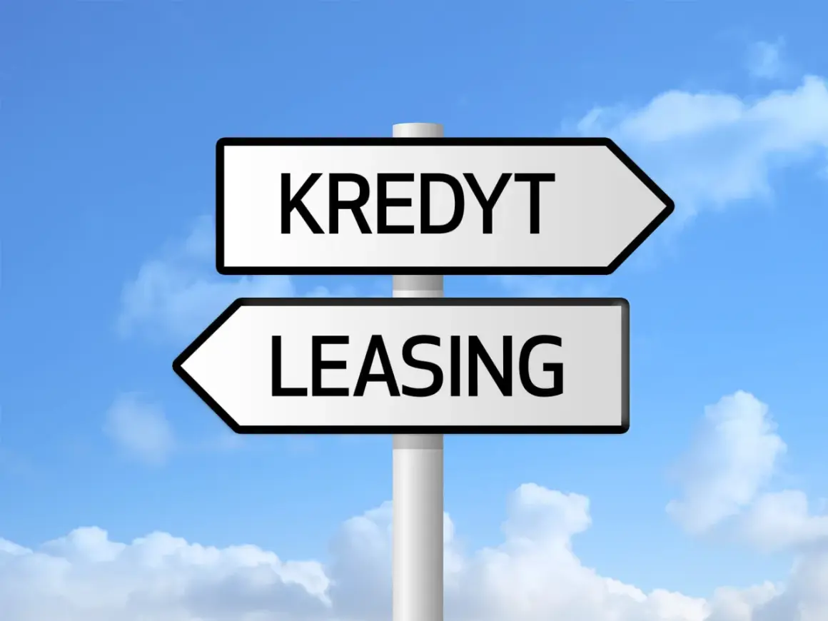 Znak drogowy z napisami "KREDYT" i "LEASING" pod niebieskim niebem z chmurami. Wybór między finansowaniem a zdolnością kredytową.