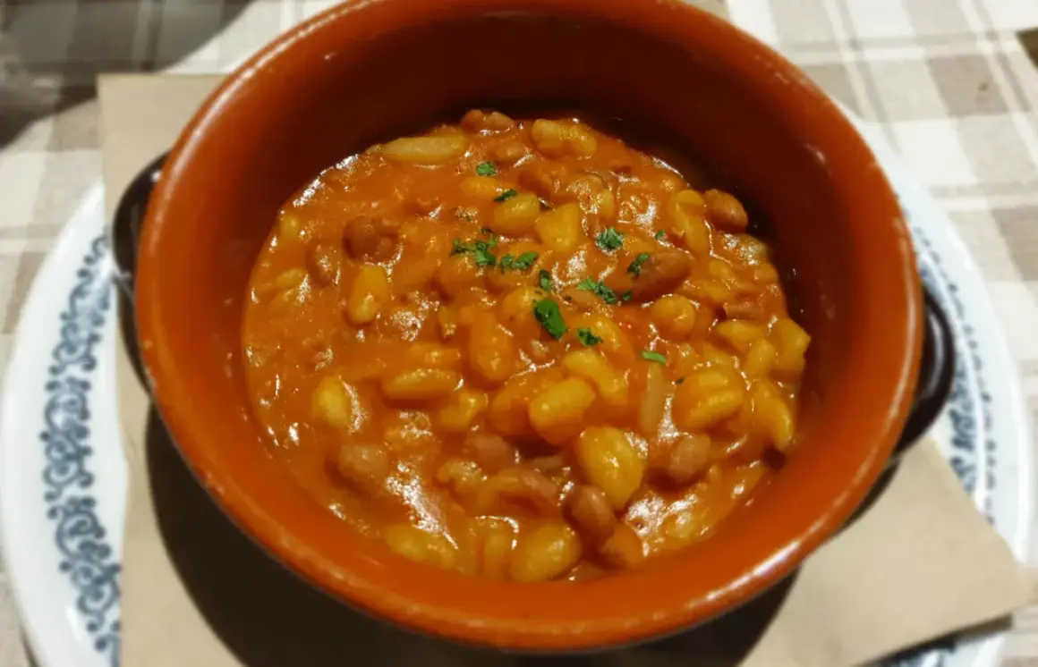 Fagioli in umido, un classico per scoprire cosa mangiare a Piacenza. Serviti in una ciotola di terracotta, sono un piatto saporito e confortante.