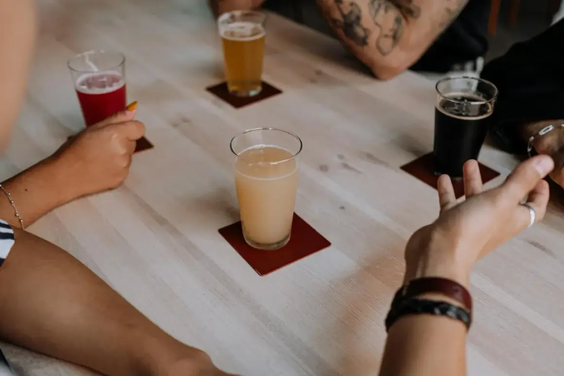 Degustacja piw belgijskich. Na stole cztery szklanki z różnymi piwami: czerwonym, jasnym, miodowym i ciemnym.